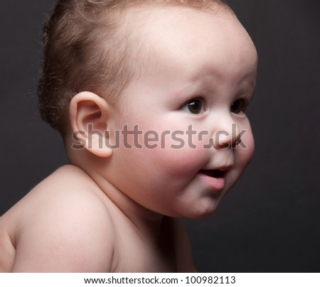 One year old baby looking to the right side with a slight smile