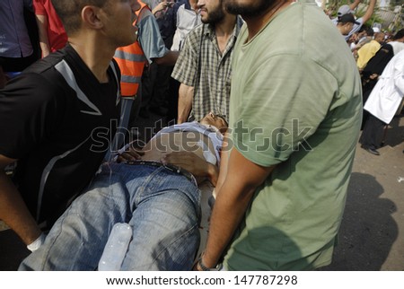 CAIRO - JULY 27: Volunteers hold an injured Morsi supporter man to makeshift hospital in Rabaa el-Adawya after he was attacked by security forces and thugs. July 27, 2013. Cairo, Egypt