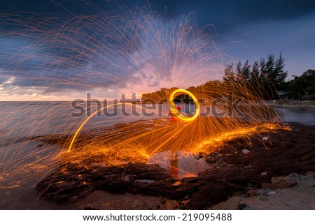 Amazing Fire dancing steel wool coast the sea in the twilight