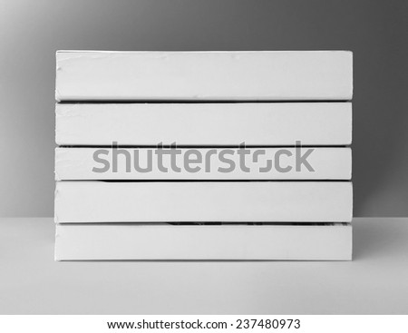 Stack of used white books with blank spine on gray background