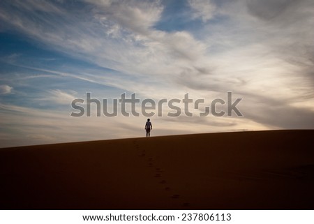 Man stands alone, on a dune in the Sahara Desert