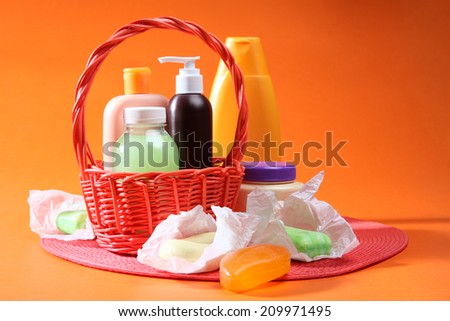 Liquid soap, shower gel, salt, cream in basket with flower