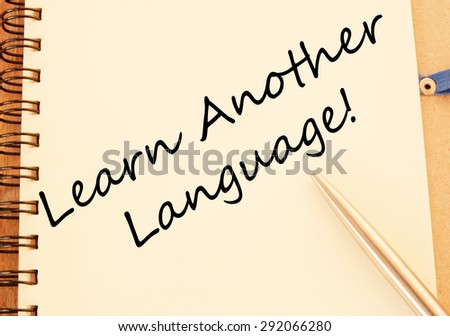 A reminder to learn another language written on a white note card and pinned to a blue notice board. A second language benefits our job prospects and helps business trade in a competitive market.
