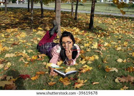 Funny college girl studying in autumn park
