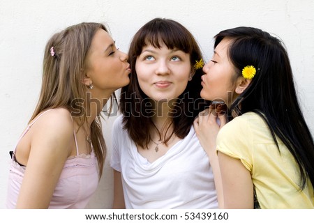 Three female friends standing in front of a white wall