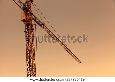 Industrial construction cranes and building silhouettes on sunset
