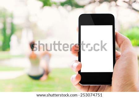 Close-up hand holding smart phone against couple and nature background