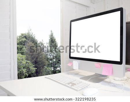 Mock up of generic design computer screen. workspace in white room against outdoor view.copy space