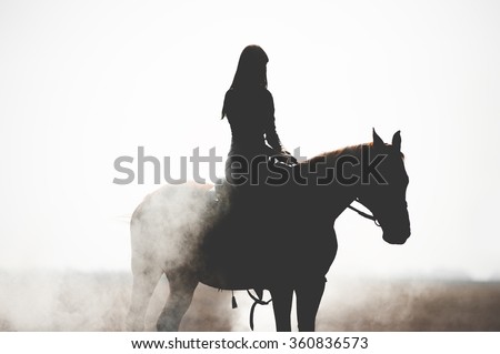 Silhouette of a beautiful girl riding a horse on a white background. Man and horse in thick smoke or fog.Brave girl leads an active lifestyle