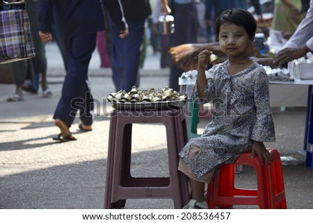 Yangon, Myanmar, February 27, 2014: Young Bells seller. A young unidentified girl selling bells in the street. In the face she has the typical Sandal-Saffron cream to protect the skin from the sun