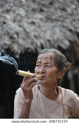 Bagan, Myanmar, March 2, 2014: asiatic old woman smoking a big handmade cigar. Image taken in a little village, the woman does cigars by herself