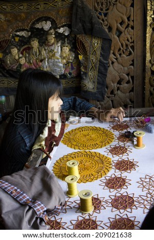 Mandalay, Myanmar, March 1, 2014: Burmese woman at work sewing beads. Close up of an artisan hand  that has sew the canvas with beads. Sewing beads onto tapestry has an ancient history in Myanmar