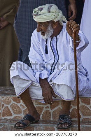Barka, Oman, October 20, 2013: An old arab man with a walking stick sit outside the daily Fish market in Barka, Oman, were fresh seafood is sold everyday