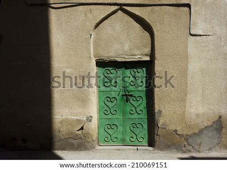 Typical omani private house door. The iron decoration remind the heart shape. A stylish door on a crumbling wall.