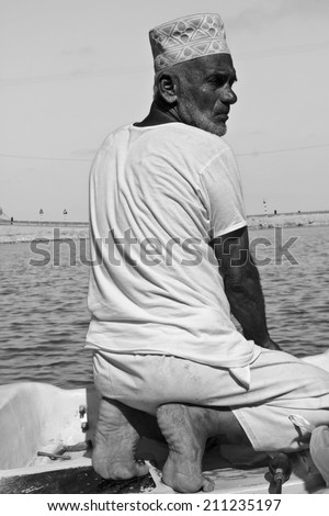 Sur, Oman, October 23, 2013: Omani fisherman at work. He is wearing the traditional omani hat, the kumma, used during unofficial time.