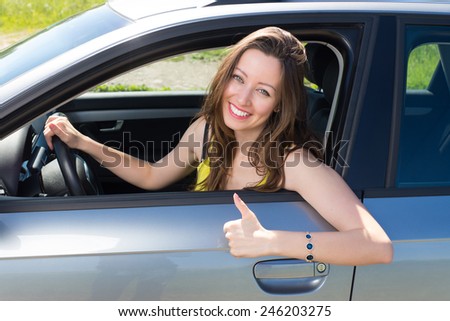 Happy smiling woman showing good sign in the car.