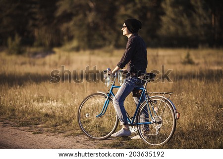 Young handsome stylish man posing with vintage bike in sunny summer day