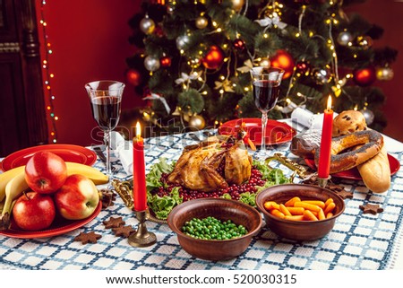 Christmas dinner by candlelight, table setting. Thanksgiving table with baked turkey in a decorated room with a Christmas tree.
