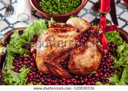 Roasted chicken, table setting. Thanksgiving table served with baked turkey, decorated with lettuce and pomegranate seeds. Christmas dinner by candlelight