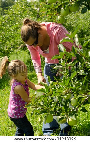 a mother and daughter picking green apples