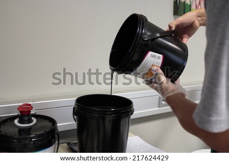 ZAGREB, CROATIA - SEPTEMBER 16, 2014: Worker in color mixing department of printing house apply UV color by color recipe for getting specified shade