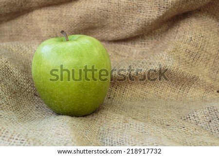 green apple on the burlap background. Copy paste