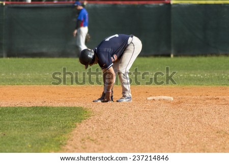 ZAGREB. CROATIA - OCTOBER 12, 2014: Baseball match Baseball Club Zagreb in blue jersey and Baseball Club Olimpija in dark blue jersey. Unidentified baseball player tied his shoes