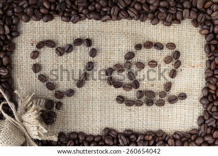 Arabica coffee beans in shape of a hart and coffee mug on burlap background in coffee beans frame