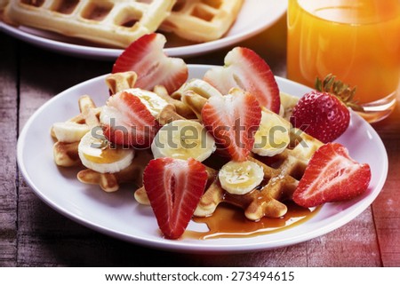 Waffles with bananas and strawberries covered with maple syrup, processed with vintage filter
