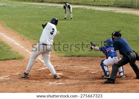 ZAGREB, CROATIA - MAY 03, 2015: Baseball match Baseball Club Zagreb in blue jersey and Baseball Club Pirates in white jersey. Baseball batter, catcher and plate umpire. Ball flying through the air