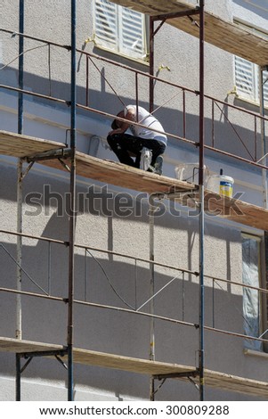 ZAGREB, CROATIA - JULY 11, 2015: Craftsman paints the facade of the house in white color