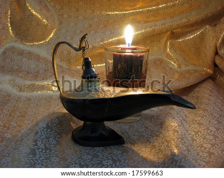 An India Aladdin\'s Lamp on a light gold background with candlelight.