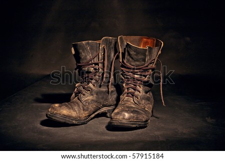 old soldier's boots worn with scratches and untied shoelaces on white background