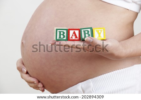 Pregnant Woman Holding Wooden Blocks Spelling Baby