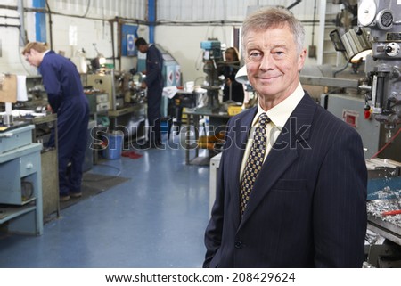 Owner Of Engineering Factory With Staff In Background