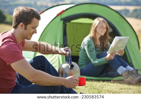 Couple Making Hot Drink Whilst Camping In Countryside