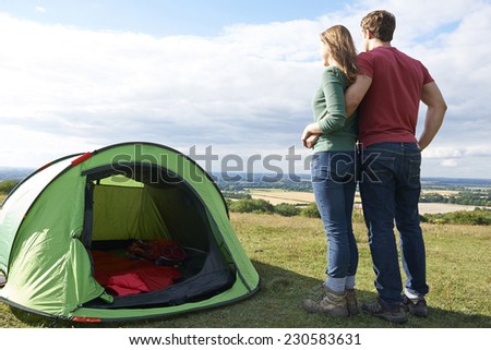 Couple Camping In Countryside Standing By Tent