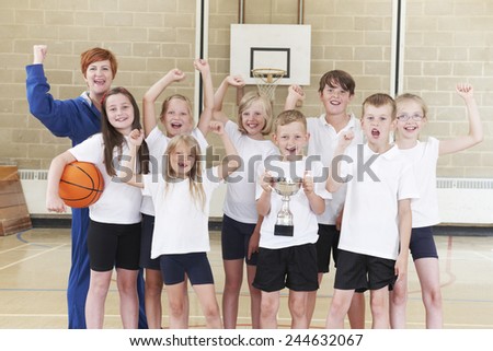 School Basketball Team And Coach Celebrating Victory With Trophy