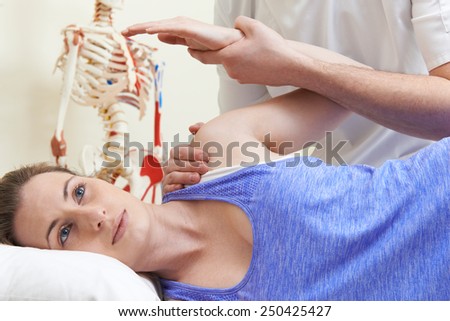 Male Osteopath Treating Female Patient With Shoulder Problem
