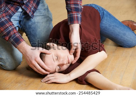 Man Placing Woman In Recovery Position After Accident