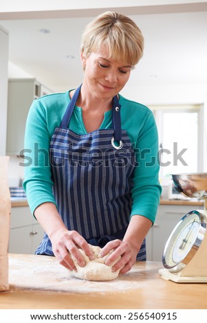 Woman Wearing Apron And Kneading Dough In Kitchen