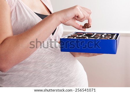Detail Of Pregnant Woman Eating Box Of Chocolates