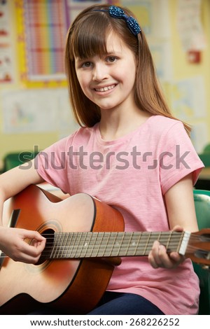 Girl Learning To Play Guitar In School Music Lesson