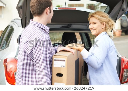 Couple Unloading New Television From Car Trunk