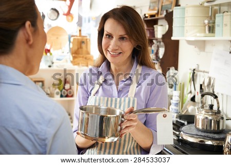 Sales Assistant In Homeware Shop Showing Customer Pan