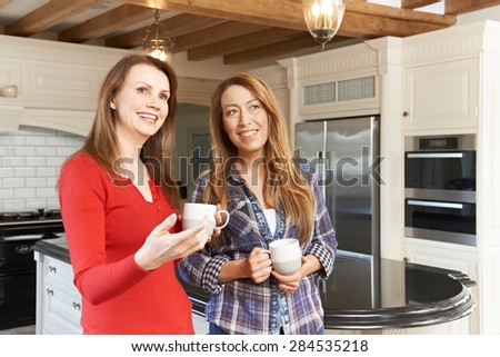 Mature Female Friends Standing In New Luxury Fitted Kitchen