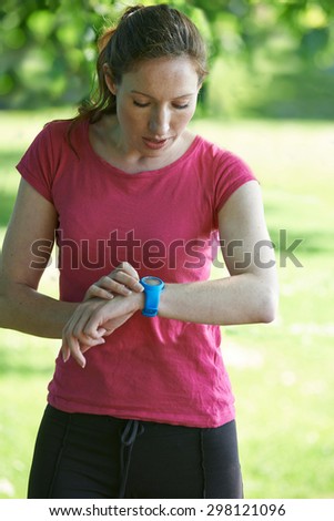 Female Runner In Park Checking Time Using Stopwatch