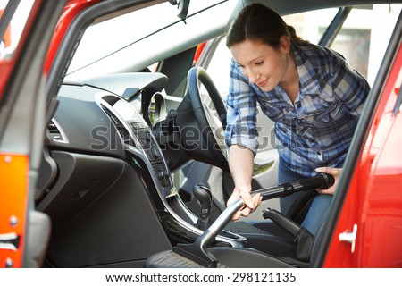 Woman Cleaning Interior Of Car Using Vacuum Cleaner