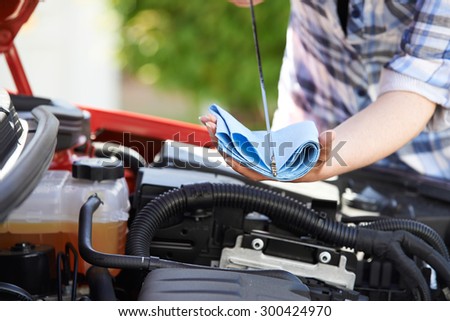 Close-Up Of Woman Checking Car Engine Oil Level On Dipstick