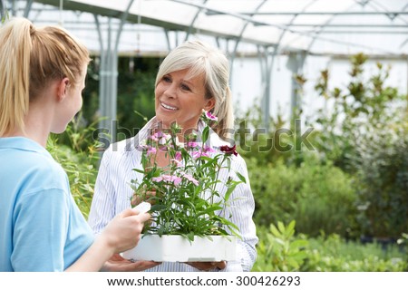 Staff Giving Plant Advice To Female Customer At Garden Center